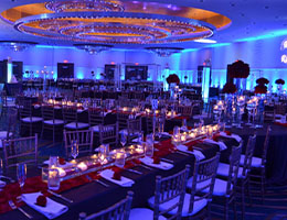 A ballroom washed in blue uplighting with candlelit tables