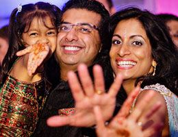A family waving mehndi-painted hands at the camera
