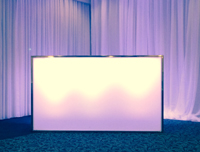 A well-lit white rectangular display stand is placed in a room with purple illuminated curtains in the background.